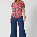 Flutter sleeved top made from breathable jersey crepe fabric is a summer staple.  Offering a relaxed fit that drapes beautifully with v neck and shirt tail hemline features. It's the ideal piece for staying cool and stylish during the summer months. Model pairs printed blouse with denim pants to style a casual ensemble. 