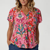 Close up image of 40 year old woman wears flutter sleeved summer printed blouse, featuring v neckline, shirt tail hemline & short flutter sleeves. Made from easy care and lightweight crepe jersey, that is breathable and comfortable. Leina & Fleur proudly stock petite and plus sizes 8-24.