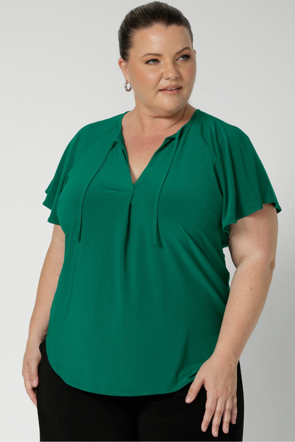 A great summer top for women, this jade green jersey top has flutter sleeve and a v-neckline. Tie neck with a curved hem. A workwear friendly comfortable style for women. Size inclusive and made in Australia for women 8-24. 