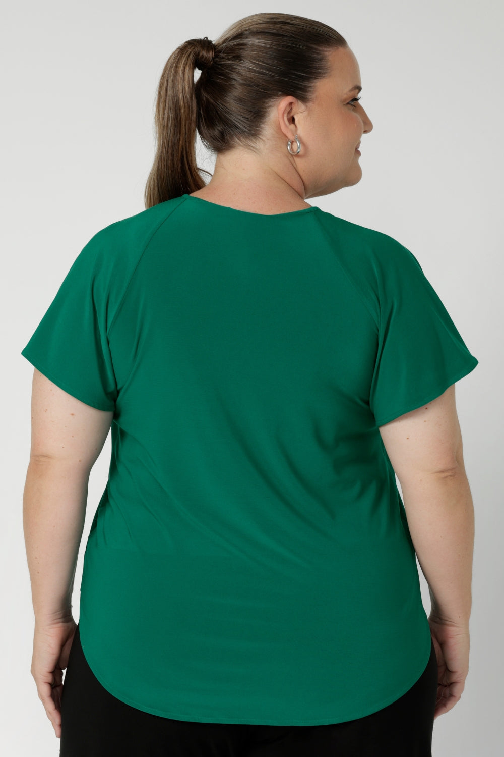 A workwear friendly comfortable style for women. Size inclusive and made in Australia for women 8-24. Plus sized model wears jade green coloured top with classic black work pants.