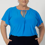 The relaxed fit offers a comfortable and slightly loose drape, while the V-neckline with thin fabric ties allows for customisation. Either left undone for a more casual feel or tied in the front for a chic, polished look. A center front pleat adds structure and subtle detail, enhancing the flattering shape of the top. Workwear top is now available in size 8-24.