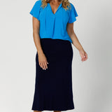 Flutter sleeve top worn by over 40's model features an easy, comfortable fit, while short flutter sleeves introduce a soft, feminine touch, creating a sense of movement with every wear. This workwear top also showcases a v neckline with neck ties that can be tied or left untied. 