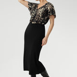Size 10 woman wears a leopard print top with black midi skirt and black high-heeled boots creating an elegant outfit for everyday.