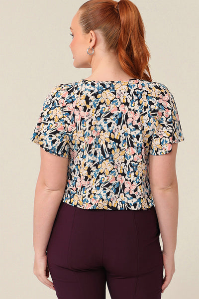 Back view of a size 12 curvy woman wearing a V-neck short sleeve jersey top with a floral print designed and made in Australia in sizes 8-24.