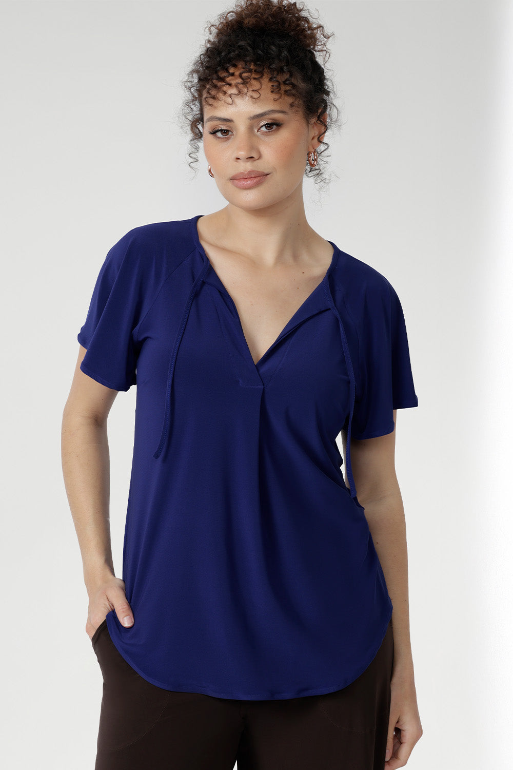 Crafted from a dry-touch jersey with gentle stretch, the Bowie Top in Sapphire offers a relaxed silhouette complemented by a V-neckline, soft pleat detailing, and tie accents. Finished with flutter sleeves and a shirttail hem, it transitions effortlessly from weekday to weekend wear.
