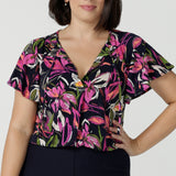 Size 10 woman wears the Bowie top in Vivid Flora with a raglan flutter sleeve, pleat front and v-neckline. Made in Australia for women size 8 - 24. 