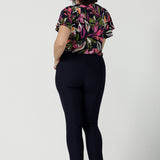 Back view of a size 10 woman wears the Bowie top in Vivid Flora with a raglan flutter sleeve, pleat front and v-neckline. Made in Australia for women size 8 - 24.