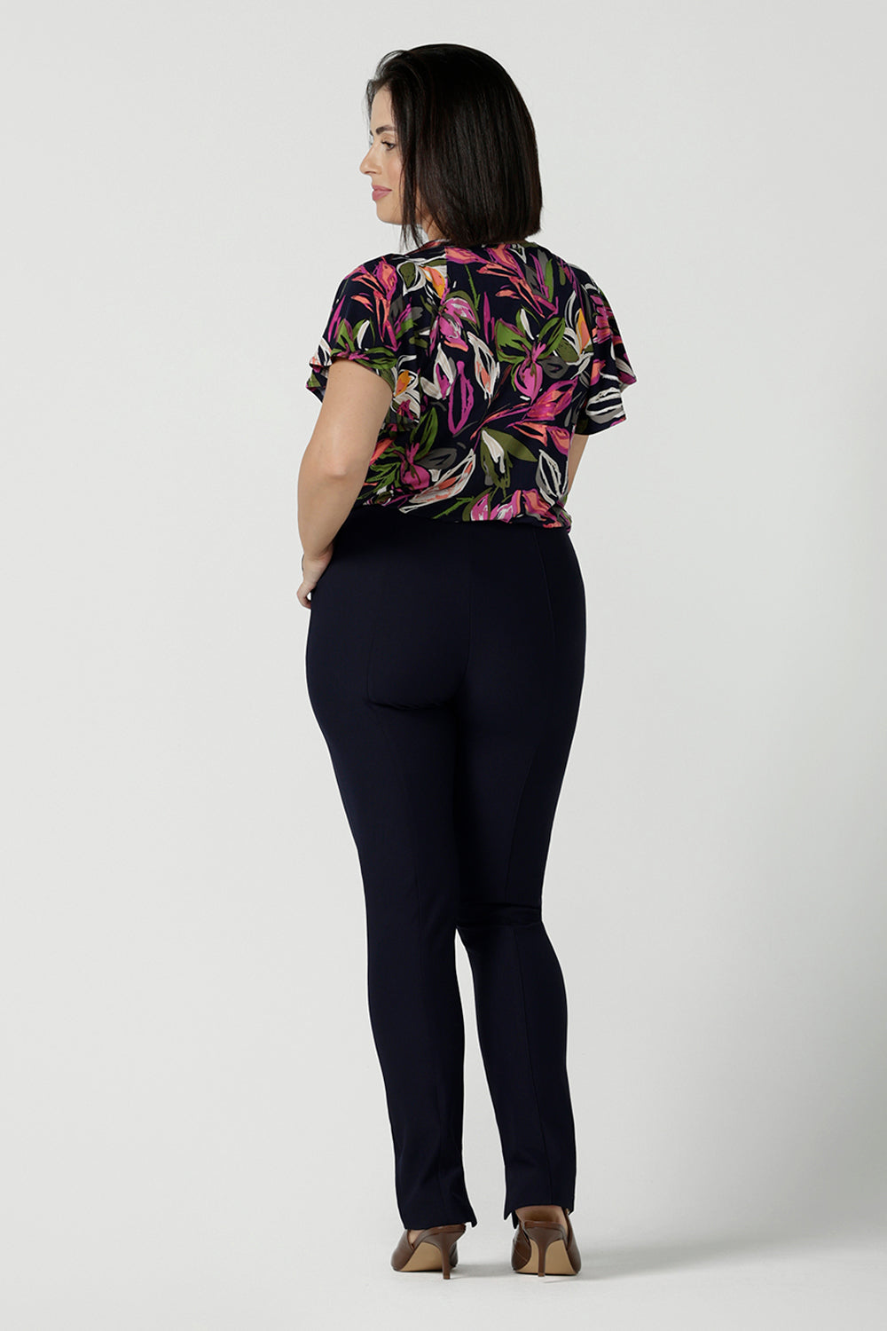 Back view of a size 10 woman wears the Bowie top in Vivid Flora with a raglan flutter sleeve, pleat front and v-neckline. Made in Australia for women size 8 - 24.