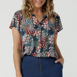 A size 10 woman wears the Bowie Top in jersey with flutter sleeves and tick neckline. Styled back with Denim Pants. Made in Australia for women size 8-24. 