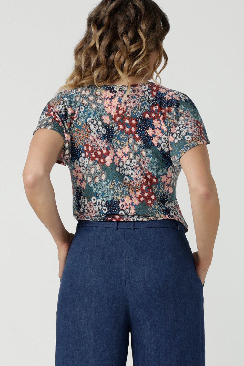 Back view of a size 10 woman wears the Bowie Top in jersey with flutter sleeves and tick neckline. Styled back with Denim Pants. Made in Australia for women size 8-24. 