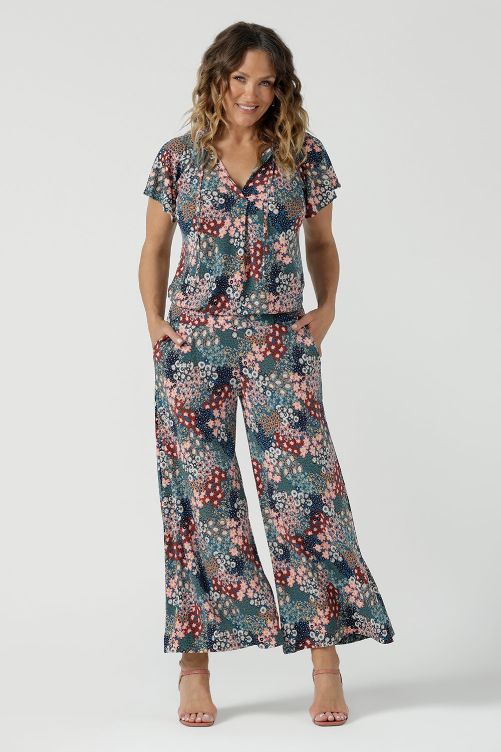 A size 10 woman wears the Bowie Top in jersey with flutter sleeves and tick neckline. Styled back with Denim Pants. Made in Australia for women size 8-24. Styled back with the Presley Pant in Whimsy. 