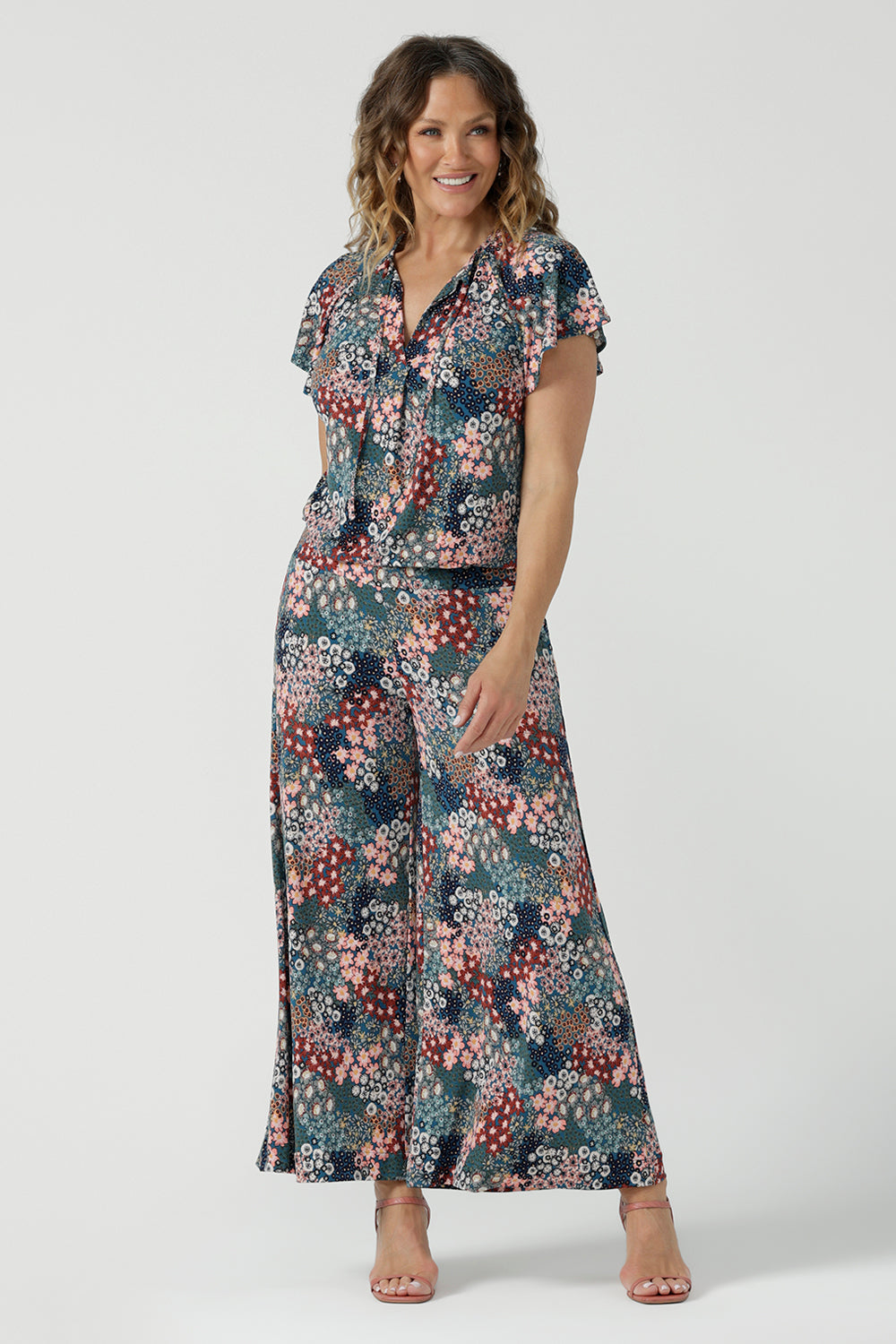 Close up of a size 10 woman wears the Presley Pant in Whimsy, a wide leg pant with a Whimsy print. A made in Australia wide leg pant with a ditsy floral print print. Size inclusive fashion for women size 8-24. Styled back with a Bowie Top in soft and comfortable jersey. 