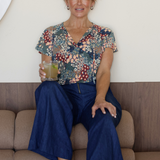 A size 10 woman wears the Bowie Top in jersey with flutter sleeves and tick neckline. Styled back with Denim Pants. Made in Australia for women size 8-24. 