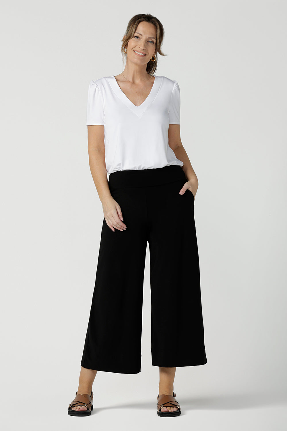 Comfortable, wide leg black culotte pants are worn with a V-neck white bamboo jersey top with short sleeves.. Cropped pants with pockets, these pull-on trousers are made in Australia by women's clothing brand, Leina & Fleur - size inclusive, shop online in petite, mid size and plus sizes.