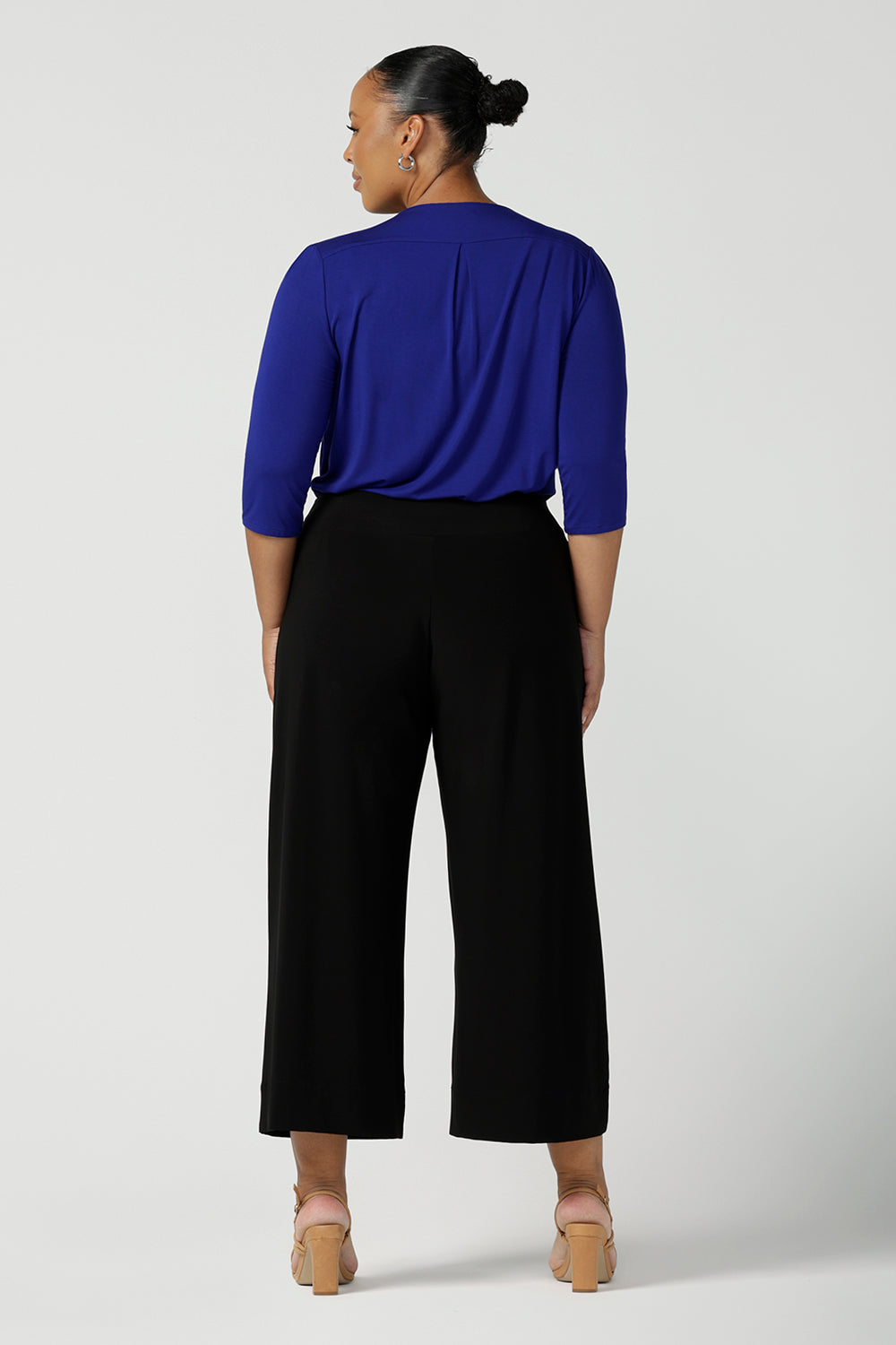 Back view of comfortable, wide leg black culotte pants are worn by a plus size, size 18 woman. Cropped pants with pockets, these pull-on trousers are made in Australia by women's clothing brand, Leina & Fleur - size inclusive, shop online in petite, mid size and plus sizes.