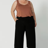 Plus sized woman wears wide leg black culotte pants. These cropped, short height  pants with pockets are a pull-on style, made in Australia by women's clothing brand Leina & Fleur. These workwear pants are size inclusive and are a considered design for woman in sizes 8-24.