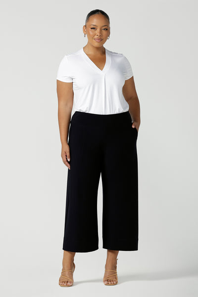 Comfortable, wide leg navy culotte pants and a V-neck white bamboo jersey top with short sleeves are worn by a plus size, size 18 woman - shop online at Australian women's clothing brand, Leina & Fleur.