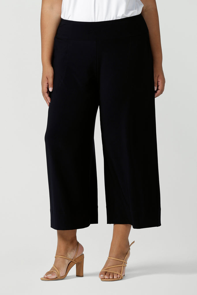 Comfortable, wide leg navy culotte pants and a V-neck white bamboo jersey top with short sleeves are worn by a plus size, size 18 woman - shop online in petite, mid size and plus sizes at Australian women's clothing brand, Leina & Fleur
