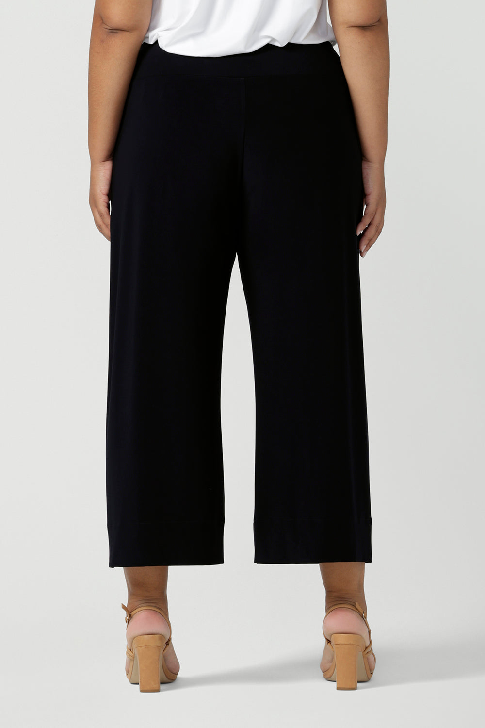 Back view of comfortable, wide leg navy culotte pants and a V-neck white bamboo jersey top with short sleeves are worn by a plus size, size 18 woman - shop online at Australian women's clothing brand, Leina & Fleur.