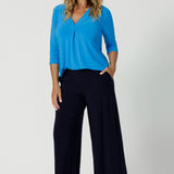 Over 40's woman wears back to work staple featuring wide leg culotte pants in the colour navy, paired with opal coloured top. Available in both regular & short lengths, considering tall and petite height women.