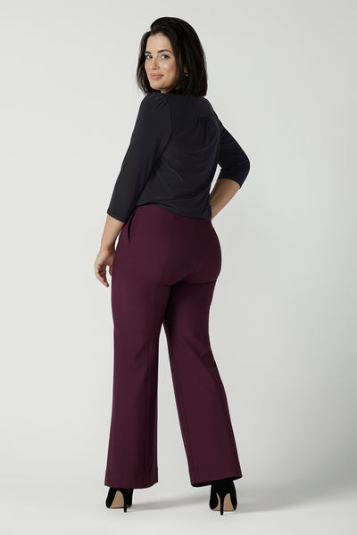 Back view of a size 10 model wearing the Brett pant in Mulberry a full length pant with a bootleg opening. Constructed in technical stretch ponte with soft tailored details. Invisible fly front zipper side pockets. Suitable for petite to tall heights. Made in Australia for corporate professional women. Size 8 - 24.