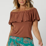 Off-the-shoulder top for summer, this slinky jersey top is a good top for over 40s style. Shown on a size 12 woman, this easy-care top is worn with printed cropped pant.  Made in Australia by Australian and New Zealand women's clothing brand, Leina & Fleur. Shop versatile clay coloured top in sizes 8-24.