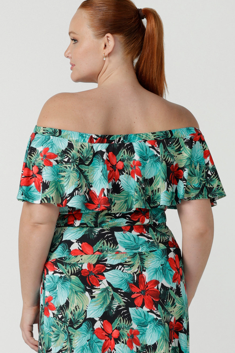 Back view of off shoulder Briar Top in Havana on a size 12 model. Tropical print design with red flowers and green palm leaf. Soft slinky jersey. Wear this top multiple ways one shoulder, off shoulder and on shoulder. Made in Australia for women size 8 - 24.