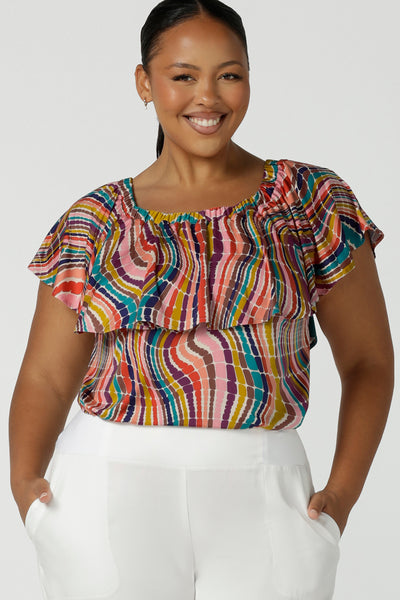 Close up of a size 16 woman wears an off shoulder top in vibrant rainbow swirl Briar top in soft slinky jersey. Made in Australia for women size 8 - 24.