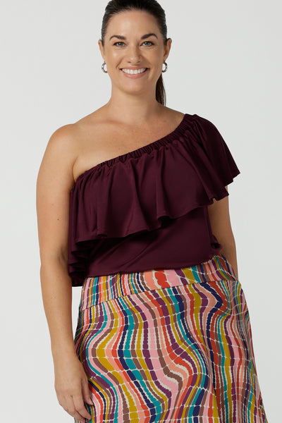 Curvy size 12 woman wears the Briar Top in Plum. A off shoulder style that can be worn in multiple ways. Wear it off or on shoulder. Deep mulberry plum colour is soft slinky jersey with ruffle frill. Made in Australia for women size 8 - 24. 