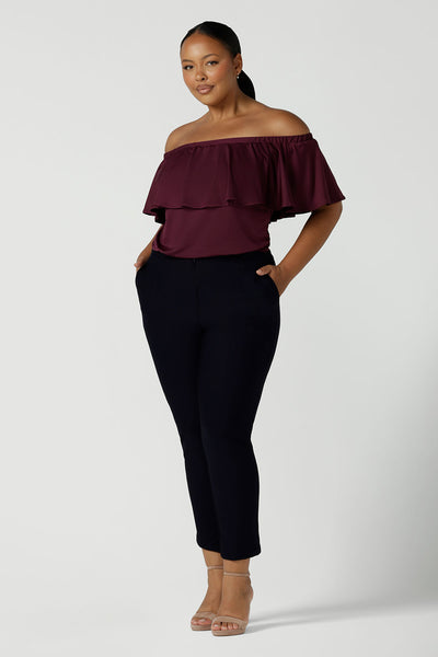 A curvy size 16 woman wears a off shoulder Briar top in Plum. Can be worn off or on shoulder with a frill neckline. Made in slinky soft jersey.  A versatile weekend top. Made in Australia size 8 -24. 