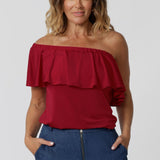 Over 40 year old woman wears red top that can be styled in 3 different ways. Top has been styled off the shoulders paired back with our Vintage Denim Dutton Pants. Made to drape beautifully with slinky jersey fabric. The vibrant colour makes it perfect for any season, adding a bold pop of colour to your wardrobe. Australian made quality, this easy care top allows you to express your unique style. Fashion label Leina and Fleur proudly stocks plus and petite sizes ranging from  8-24.