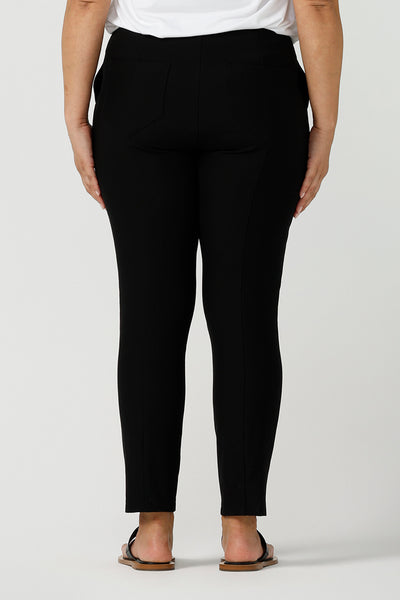 Back view of a size 12 woman wearing a slim leg, cropped length black pants for work wear and weekend wear are worn with a V-neck white bamboo jersey top with flutter sleeves. These stretchy women's trousers make great pants for your capsule wardrobe. Made in Australia by Australian and New Zealand women's clothing label, L&F.