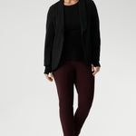 Size 10 woman wears knit top under black work wear blazer. Designed for comfort and versatility, it features a flattering close-to-body fit that moves with you, thanks to its generous stretch and breathable finish. Black knit top has thumbholes that can be used or tucked away for versatility in styling and extra warmth. Available in size 8-24.