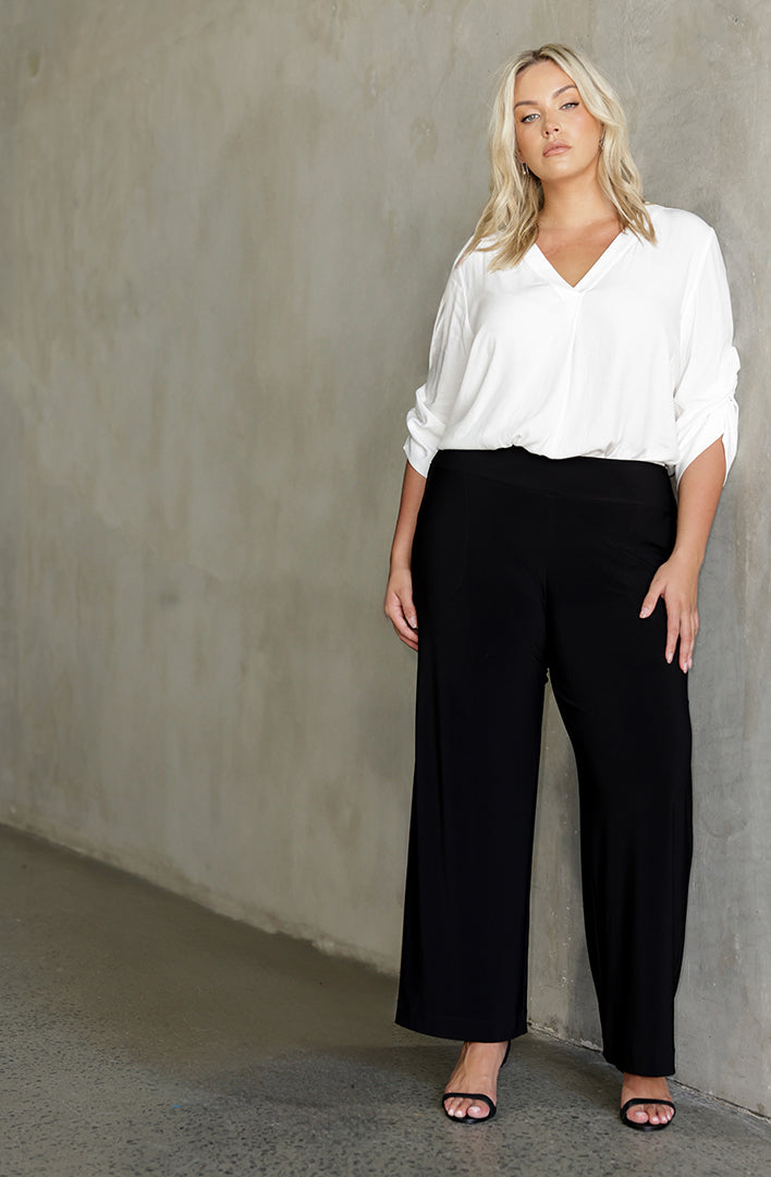 Great black pants for plus size women, a curvy woman wears size 18 work wear pants with a white 3/4 sleeve blouse.