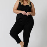 Showing a good loungewear cami top for curve women, a size 18 woman wears a plus size cami top in black bamboo jersey. Thermo-regulating this sleepwear top is a good top for menopause and night sweats. Cami top is Worn with tapered leg lounge pants. Shop lounge wear tops online in sizes 8-24.