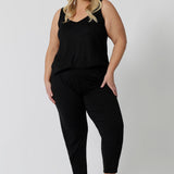 Showing a good lounge wear cami top for curve women, a size 18 woman wears a plus size cami top in black bamboo jersey. Thermo-regulating this sleeveless sleepwear top is a good top for menopause and night sweats. This black Cami top is Worn with tapered leg lounge pants. Shop lounge wear tops online in sizes 8-24.