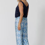 Back view of a pretty blue  pyjama set that's great for over 40s women. A size 12 woman wears straight leg pyjama pants with blue and white print and a navy blue bamboo jersey cami top with wide shoulder straps. Thermo-regulating and breathable, these pajama pants with drawstring ties are good pyjamas for night sweats and hot flushes. Shop this loungewear set online at L&F Australia in sizes 8 to 24.