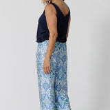 Back view of a pretty blue  pyjama set that's great for over 40s women. A size 12 woman wears straight leg pyjama pants with blue and white print and a navy blue bamboo jersey cami top with wide shoulder straps. Thermo-regulating and breathable, these pajama pants with drawstring ties are good pyjamas for night sweats and hot flushes. Shop this loungewear set online at L&F Australia in sizes 8 to 24.