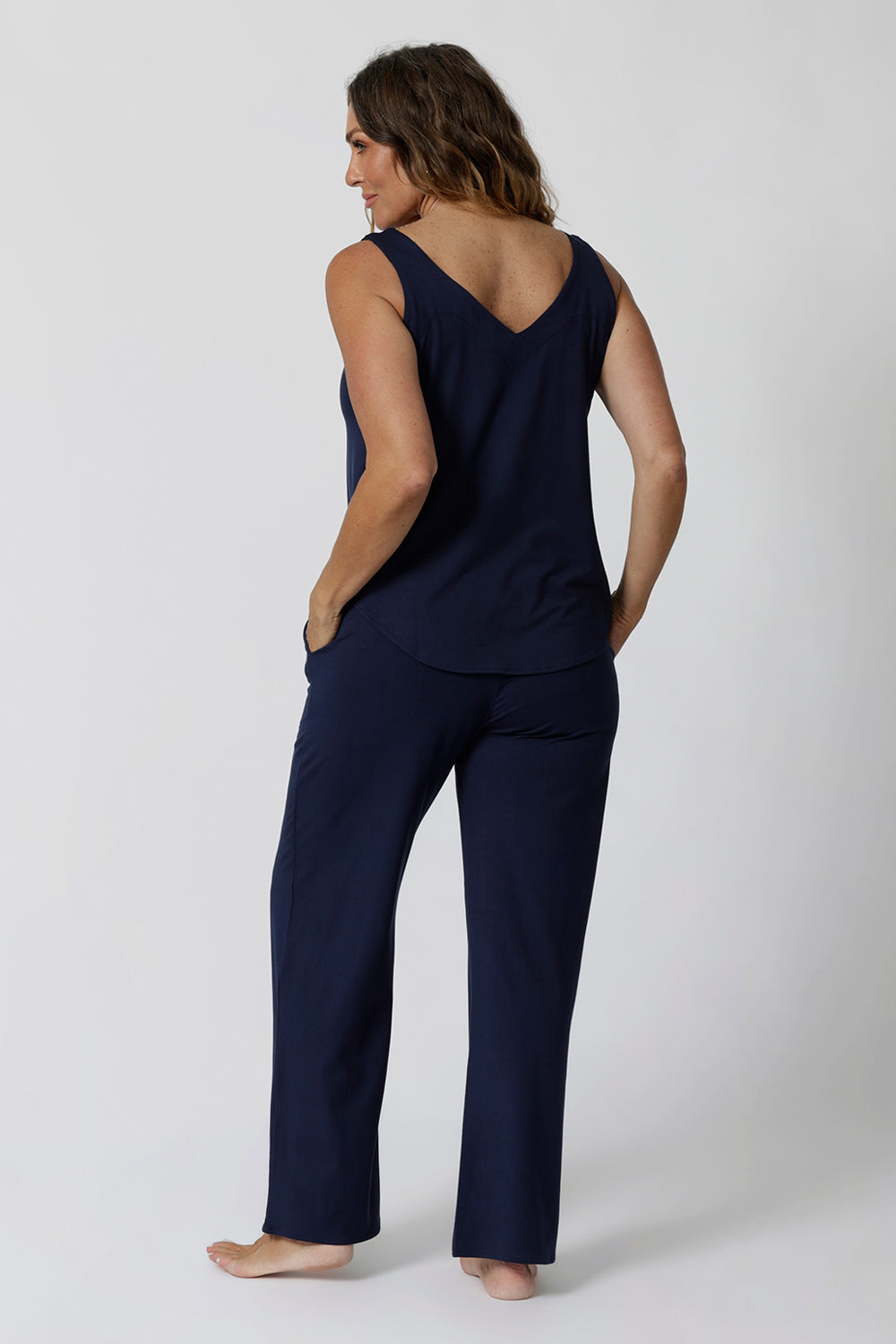 Back view of good lounge pants for over 40s women, a size 12 woman wears straight, wide leg navy blue, plus size lounge pants in bamboo jersey with a blue bamboo jersey cami top. Breathable and thermo-regulating this is a good pyjama set  for night sweats and hot flushes. Stay cool for summer nights and shop breathable sleepwear by L&F Australia in sizes 8-24.