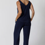 Back view of good lounge pants for over 40s women, a size 12 woman wears straight, wide leg navy blue, plus size lounge pants in bamboo jersey with a blue bamboo jersey cami top. Breathable and thermo-regulating this is a good pyjama set  for night sweats and hot flushes. Stay cool for summer nights and shop breathable sleepwear by L&F Australia in sizes 8-24.