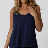 An over 40s woman wears a size 12 cami top in navy bamboo. This V-neck cami top is worn with navy bamboo jersey lounge pants as cooling pajamas for night sweats. Shop pyjamas for menopause in sizes 8 to 24 online at L&F Australia,