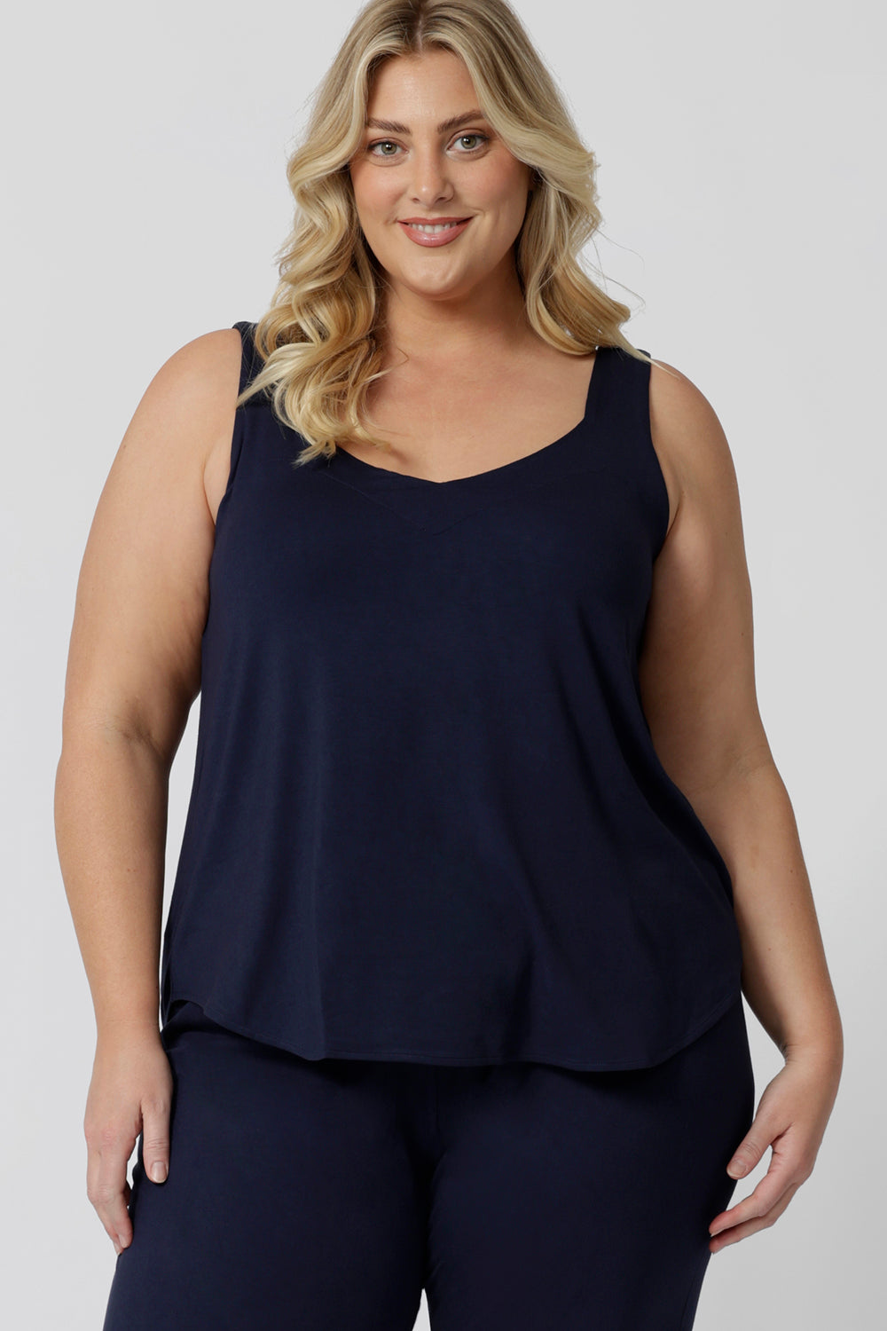 An curvy woman wears a size 18 cami top in navy bamboo. This plus size cami top is worn with navy bamboo jersey lounge pants as cooling pajamas for night sweats. Shop women's plus size pyjamas for menopause in sizes 8 to 24 online at L&F Australia,