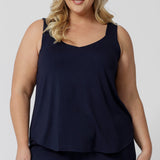 An curvy woman wears a size 18 cami top in navy bamboo. This plus size cami top is worn with navy bamboo jersey lounge pants as cooling pajamas for night sweats. Shop women's plus size pyjamas for menopause in sizes 8 to 24 online at L&F Australia,