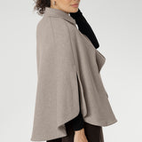 The tailored silhouette is enhanced with three front buttons that fasten cleanly across the chest, while a cleverly designed waistband wraps around the back and threads through discreet loop holes to cinch the waist and define your shape. Arm slits crafted into the sides allow for natural movement and create a graceful flare as you walk, adding fluidity and ease to every step.