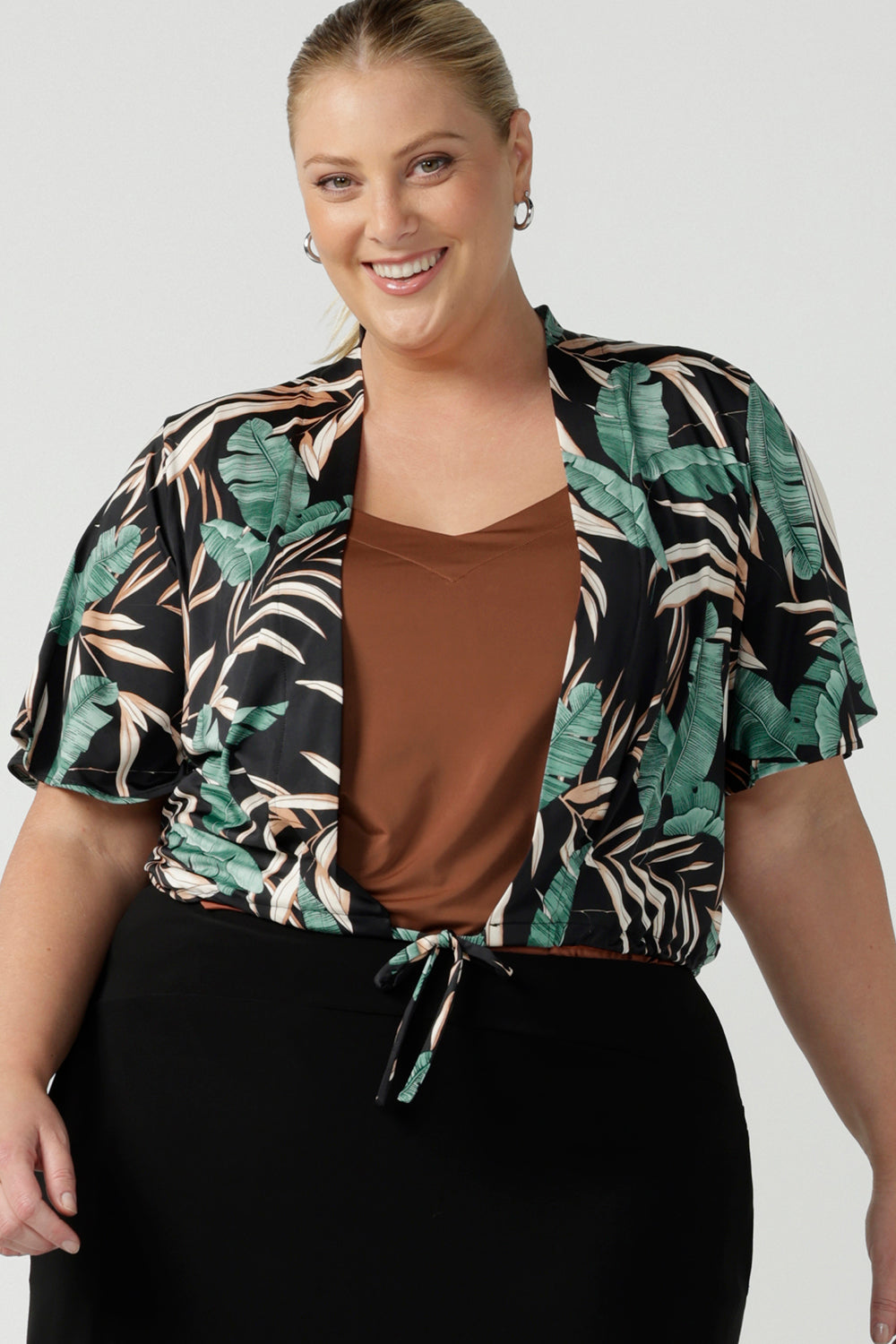 Tropical printed shrug cardigan. Featuring a leaf print on a black background. Ruched waist tie detail tie detail. Great layering piece. Ladies inclusive sizing. 