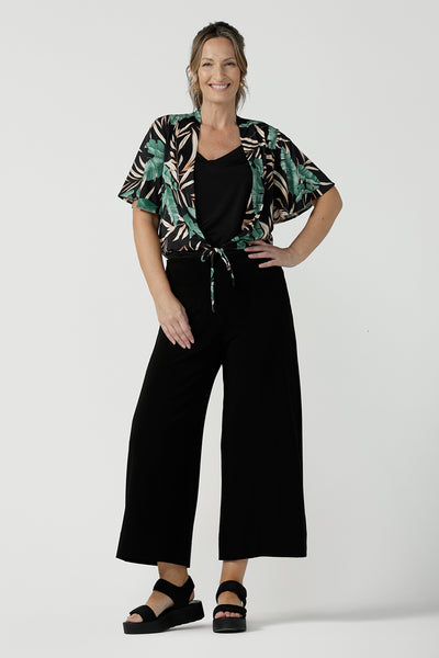 Tropical printed shrug cardigan. Featuring a leaf print on a black background. Ruched waist tie detail tie detail. Great layering piece. Ladies inclusive sizing. Size 8 pictured.
