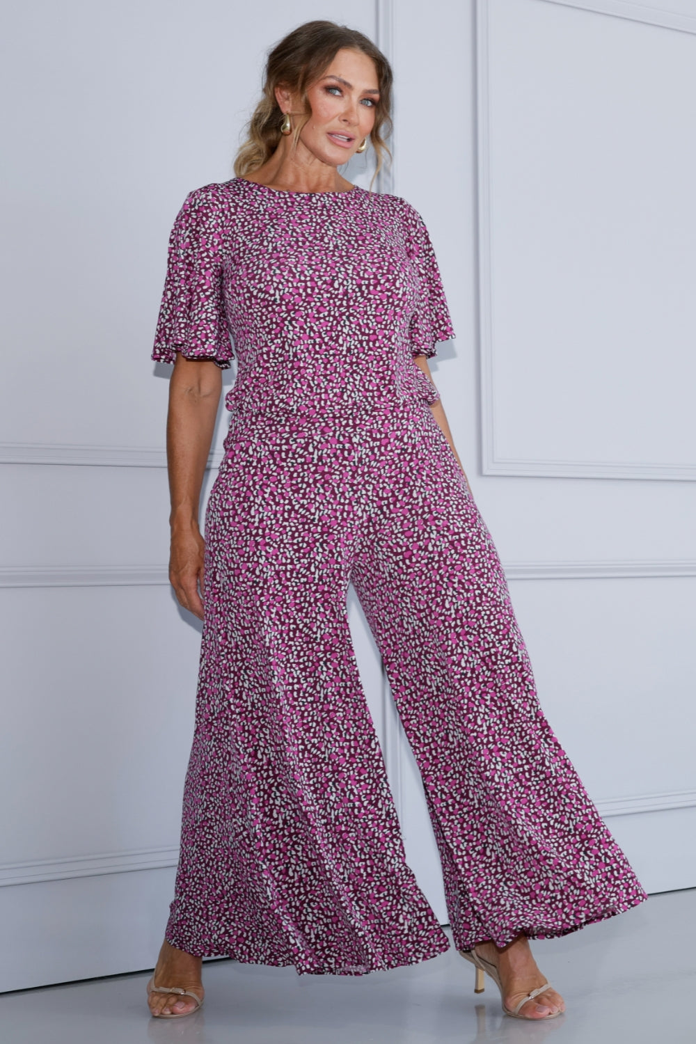 These pants can be styled in various ways: pair them with the matching top for a chic faux jumpsuit effect, or wear them with a simple block colour for a more minimalist look. Size 12 woman wears her Bordeaux inspired jumpsuit with nude heels and gold accessories. 