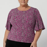 Chloe’s flutter sleeves, sitting just above the elbow, bring a sense of occasion and feminine flair, making this top perfect for both casual and more dressed-up looks. Plus size woman wears size 18 top paired with black skirt.