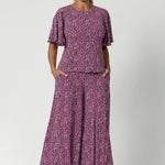 The rich tones of magenta, pink, graphite, and vanilla come together in a stunning print that catches the eye while remaining versatile enough to pair with a variety of pieces. Whether you're dressing for a special occasion or adding a touch of elegance to your everyday wear, Chloe will have you feeling chic and confident. Size 12 model wears the printed top with matching printed palazzo pants for a jumpsuit look. 