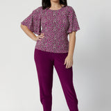 The rich tones of magenta, pink, graphite, and vanilla come together in a stunning print that catches the eye while remaining versatile enough to pair with a variety of pieces. Petite height model wears easy care top with magenta coloured pants and nude heel for an elevated look. Sizes 8-24 available in the Chloe Tops